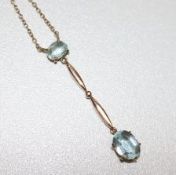 An early 20th century gold and aquamarine drop pendant necklace, set with two oval cut stones on a