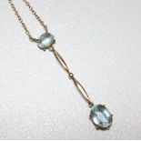 An early 20th century gold and aquamarine drop pendant necklace, set with two oval cut stones on a