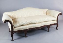 A George III style mahogany camel back settee, carved with flowers and scrolls, on lions paw feet,