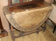 A 1920's carved oak gateleg table, W.104cm