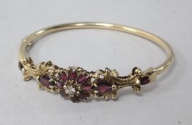 A gold, diamond and garnet set hinged bangle.