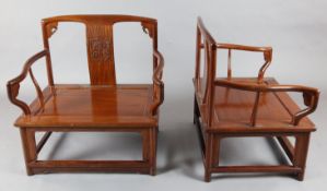 A pair of Chinese hardwood low open armchairs, the backs carved in relief with archaistic scrolls