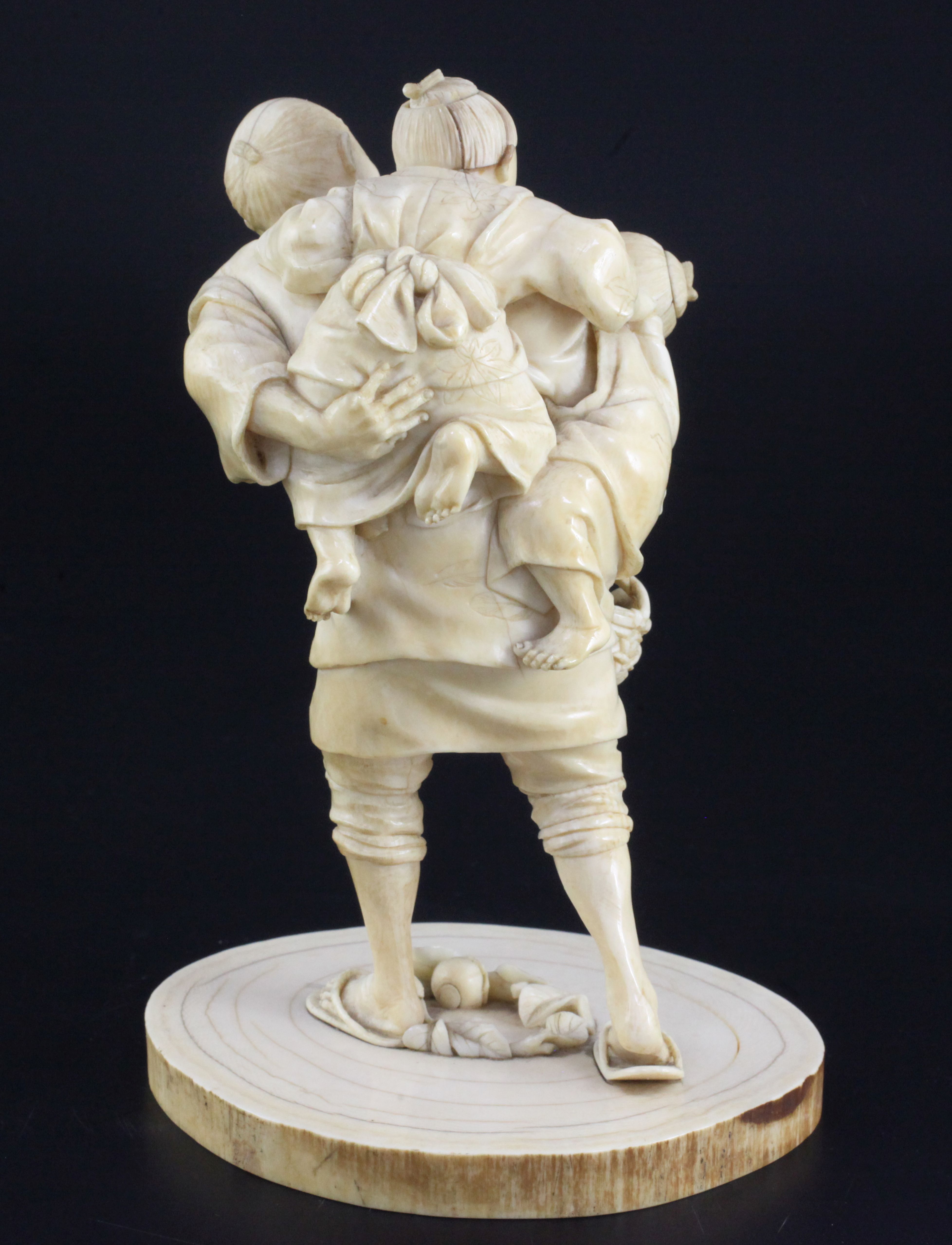 A Japanese ivory group of a man carrying two boys, Meiji period, one boy holding a basket of - Image 2 of 3