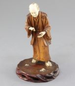 A Japanese ivory and boxwood okimono of a man, early 20th century, in standing pose, on a hardwood
