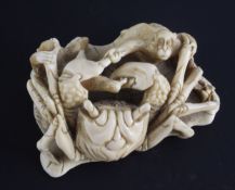 A Japanese marine ivory okimono of a crab battling two monkeys, early 20th century, on a curled