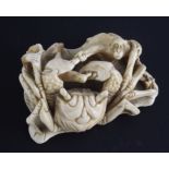 A Japanese marine ivory okimono of a crab battling two monkeys, early 20th century, on a curled