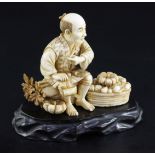 A Japanese ivory okimono of a farmer smoking a pipe, early 20th century, seated amid his crop of