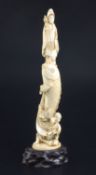 A Japanese ivory okimono of Kwannon standing upon a giant carp, early 20th century, supported by a