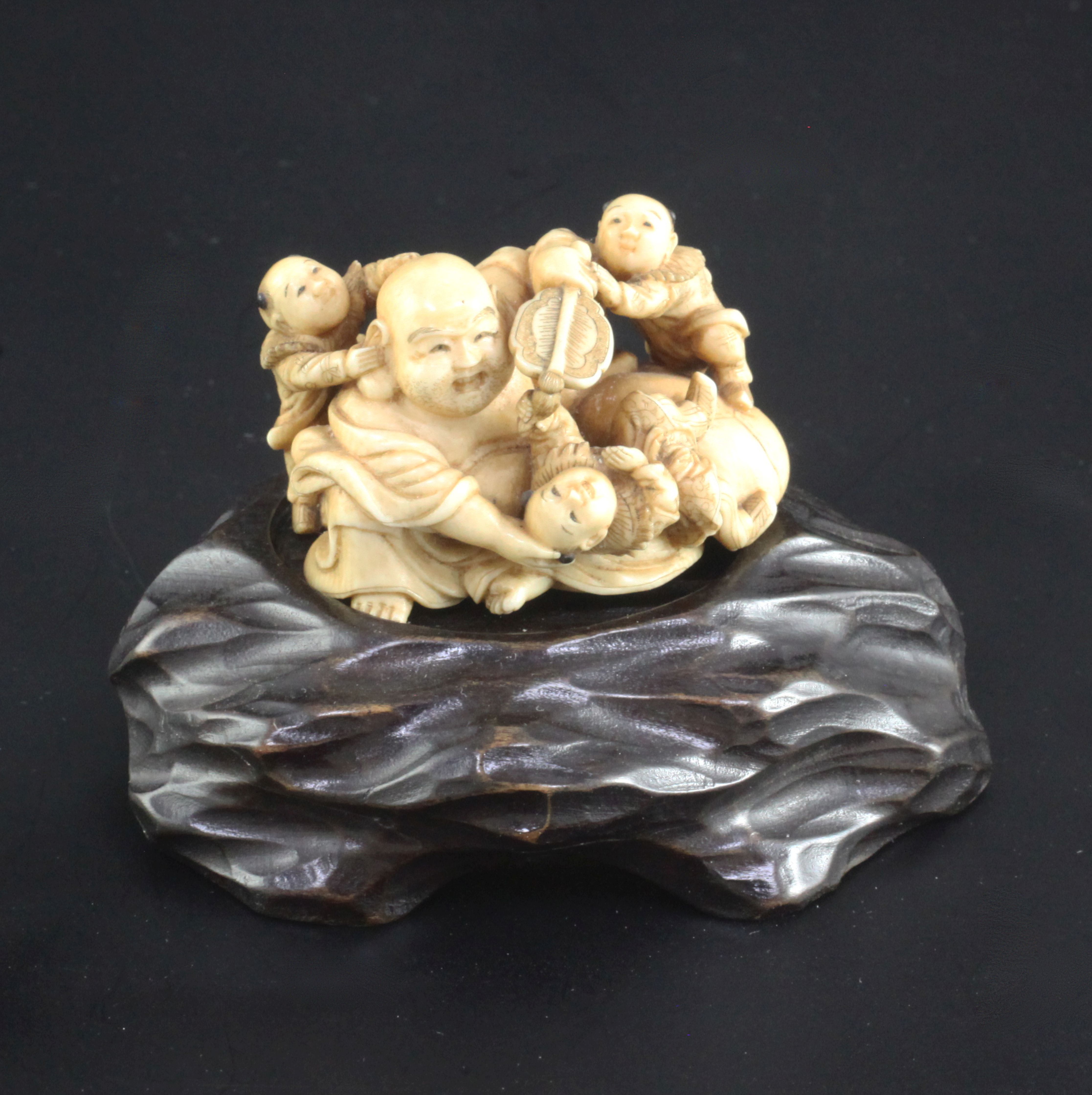 A Japanese ivory okimono of Hotei and three boys, signed Ikkosai, Meiji period, the boys