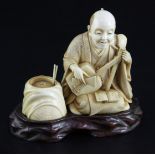 A Japanese ivory okimono of a kneeling musician, early 20th century, with brocade pattern robes