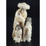 A Japanese walrus ivory okimono of a woman and three children, with engraved robes, two character