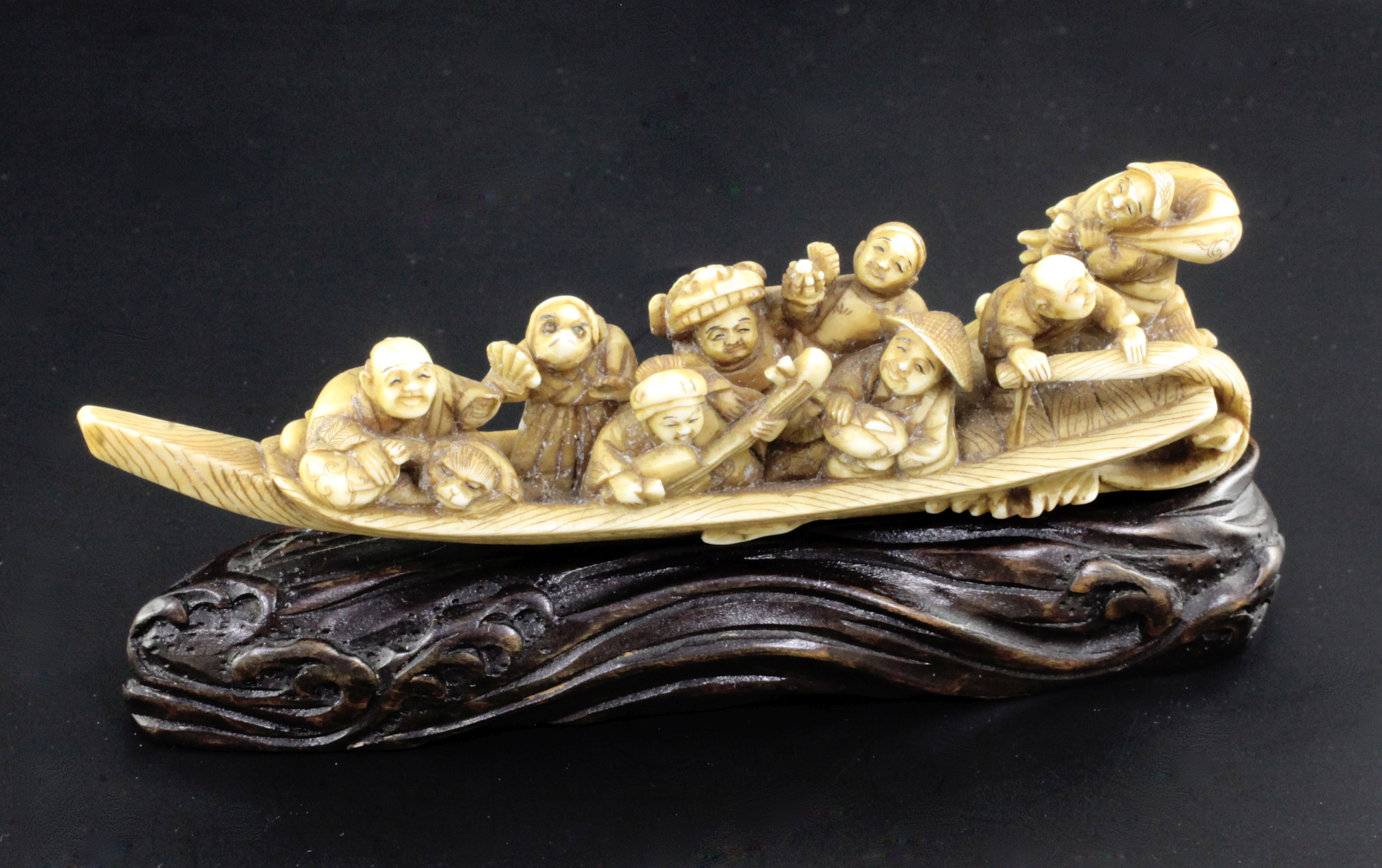 A Japanese ivory okimono of figures enjoying festivities on a boat, Meiji period, playing music