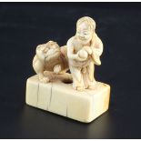 A Japanese ivory netsuke of Binzuru rakan and a tiger, Edo period, standing on a rectangular seal