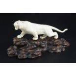 A Japanese ivory figure of a prowling tiger, signed Gyoku..? Meiji period, with glass inset eyes,