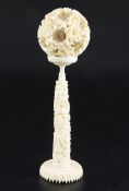 A Chinese ivory concentric puzzle ball and stand, early 20th century, the ball carved in high relief