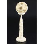 A Chinese ivory concentric puzzle ball and stand, early 20th century, the ball carved in high relief