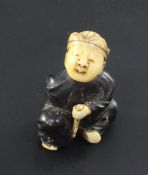 A Japanese wood, lacquer and ivory netsuke, Meiji period, modelled as a seated boy holding a fan and