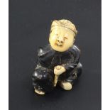 A Japanese wood, lacquer and ivory netsuke, Meiji period, modelled as a seated boy holding a fan and
