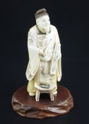 A Japanese ivory figure of a scholar, early 20th century, holding a calligraphy brush and a