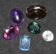 Five unmounted cut gemstones including a cabochon amethyst and a paste stone.