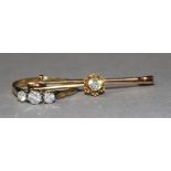 A gold and three stone diamond ring and a solitaire diamond set bar brooch.