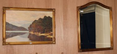 An arched gilt frame wall mirror, and an oil lake scene, W.70cm, H.90cm
