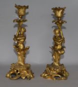 A pair of gilded putti candlesticks