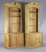 A near pair of classical style pine open bookcases, with broken arch pediments, fluted sides and
