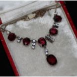 A garnet and white stone pendant necklace.