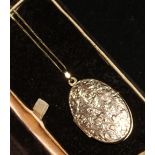 An engraved 9ct gold oval locket on a gold chain.