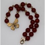 A 9ct gold and carnelian bead and butterfly necklace, 15in.