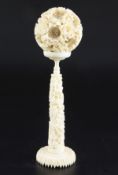 A Chinese ivory concentric puzzle ball and stand, early 20th century, the ball carved in high relief