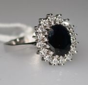 A 14ct white gold, sapphire and diamond cluster ring, size M.