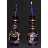 A pair of gilded and enamelled blue glass decanters and stoppers