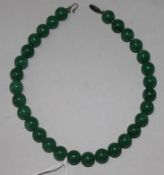 A necklace of thirty polished green jade beads, 14.25in.