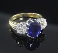 An 18ct gold and three stone sapphire and diamond ring, the central oval cut sapphire weighing in
