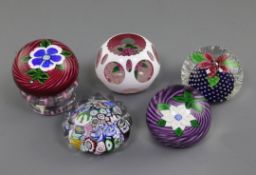 Five John Deacons glass paperweights; a piedouche with a blue and white flower on a red spiral