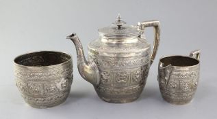 A late Victorian Scottish Indian style silver three piece tea set by James Reid & Co, embossed