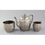 A late Victorian Scottish Indian style silver three piece tea set by James Reid & Co, embossed