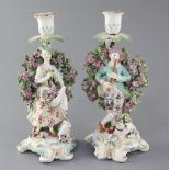 A pair of Derby candlestick figures, c.1770, modelled as a lady holding flowers in her apron and a