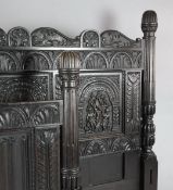 A 17th century style ebonised oak bedstead, with acanthus and linen-fold carved panels and stop-