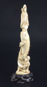 A Japanese ivory okimono of Kwannon standing upon a giant carp, early 20th century, supported by a