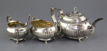 A George III demi fluted silver three piece oval tea set, with gadrooned borders, on paw feet, IP,