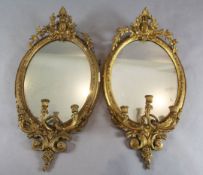 A pair of Victorian gilt gesso three light girandoles, with laurel crests and oval plates, W.1ft