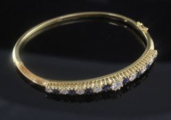 A modern 18ct gold, diamond and sapphire hinged bangle, set with seventeen graduated stones.