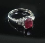A modern 18ct white gold, ruby and diamond ring, with central emerald cut ruby, flanked by