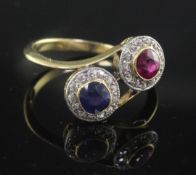 A mid 20th century 18ct gold, ruby, sapphire and diamond double cluster crossover ring, size P.