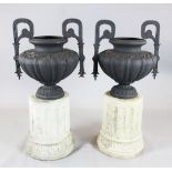 A pair of cast iron two handled urns, on reconstituted stone plinths, W. 1ft 11in. height overall
