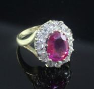 An 18ct gold, burmese ruby and diamond set oval cluster ring, the 3.30ct ruby with accompanying