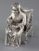 A late 19th century German Hanau silver model of an elderly lady sewing, seated in an ornate antique